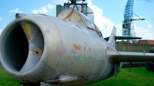 Close-up of airplane on field against sky