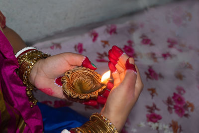 Hands of an indian woman holding diya or pradip on diwali festival. selective focus on pradip.
