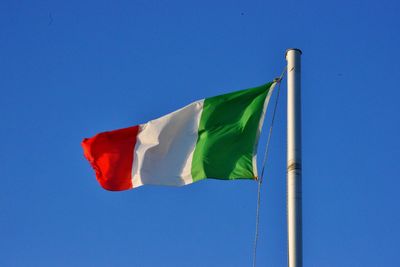 Low angle view of flag against blue sky