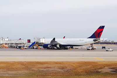 Airplane on airport runway against sky