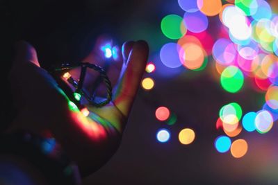 Cropped hand of person holding illuminated colorful lighting equipment