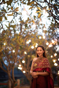 Portrait of smiling young woman standing by tree