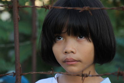 Close-up of cute girl standing by fence