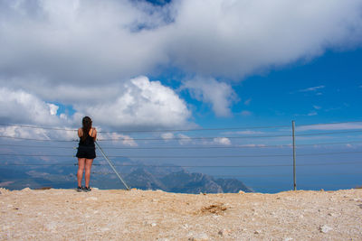 Rear view of woman standing on land against sky