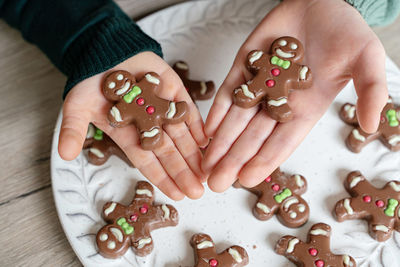 Cropped hand of boy holding gingerbread cookies in plate