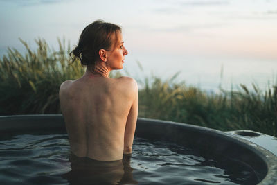 Side view of shirtless man standing in water