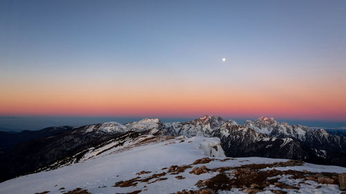 Scenic view of snowcapped mountains against sky during sunset