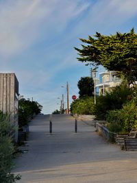Road amidst trees and buildings against sky