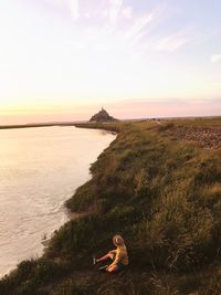 Man looking at sea against sky during sunset