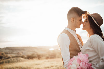 Rear view of couple kissing against sky