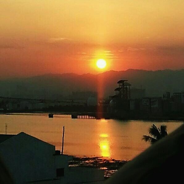 sunset, sun, orange color, water, sky, built structure, architecture, scenics, beauty in nature, building exterior, tranquil scene, nature, sunlight, tranquility, reflection, idyllic, river, silhouette, mountain, cloud - sky