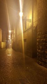 Illuminated street amidst buildings at night