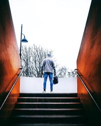 Rear view of man on staircase against sky