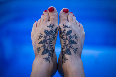 Low section of woman with tattoo against water