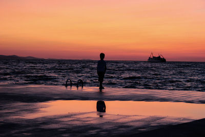 Silhouette man standing on beach against sky during sunset