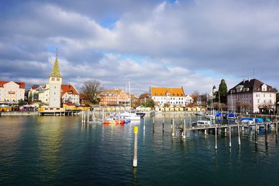 Sailboats in canal by buildings against sky in city