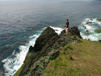 High angle view of man standing on rock by sea