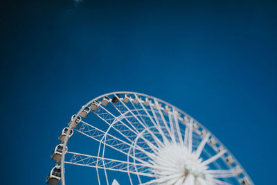 Low angle view of ferris wheel against blue sky