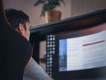 A young caucasian guy sits in a work chair and browses the news feed on the social network