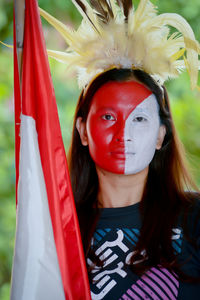 Portrait of woman with face paint standing against trees