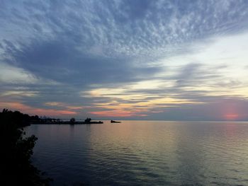 Scenic view of sea against cloudy sky at sunset