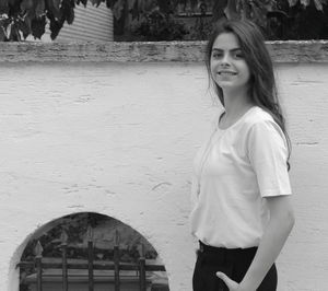 Portrait of smiling woman standing against wall