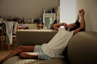 Midsection of girl sitting on sofa at home