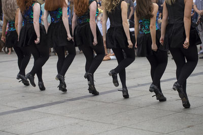 Low section of women dancing in row on city street