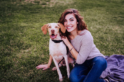 Portrait of woman with dog sitting on grass