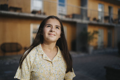 Smiling girl looking up among residential buildings