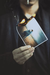 Midsection of man holding burning photograph