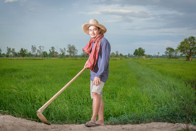 Portrait of man standing on field against sky