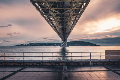 Bridge over sea against sky during sunset