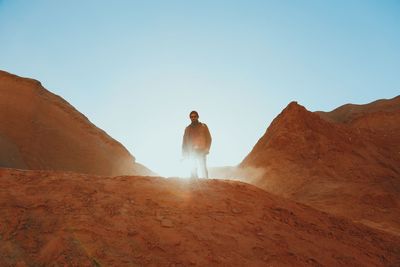 Low angle view of man standing on mountain against clear sky