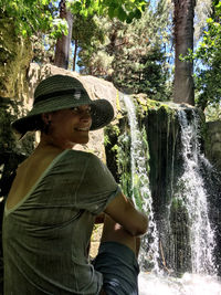 Portrait of woman sitting by waterfall in forest