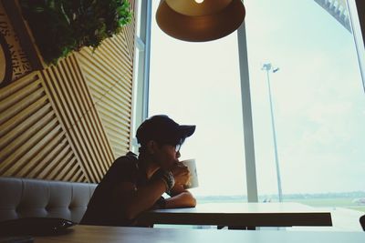 Woman having drink while sitting at table in cafe