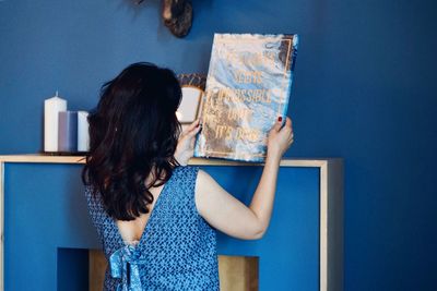 Rear view of woman standing against blue wall