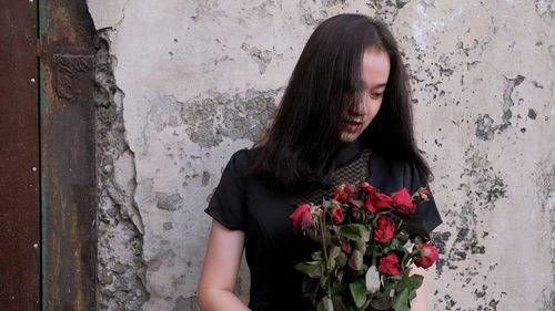 Low section of woman standing hold roses