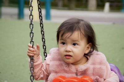 Cute baby girl sitting on swing at playground