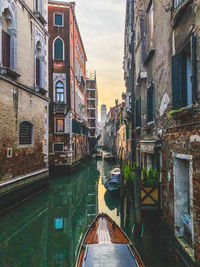 Rear view of man on canal amidst buildings in city