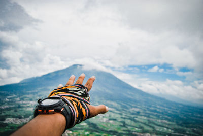 Cropped hand against mountain