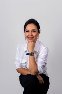 Portrait of young woman standing against white background