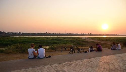 Group of people sitting in park at sunset
