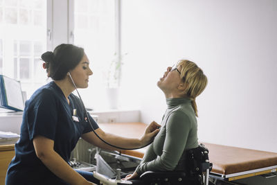 Female nurse examining patient with disability in clinic