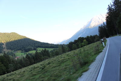 Road amidst trees and mountains against sky