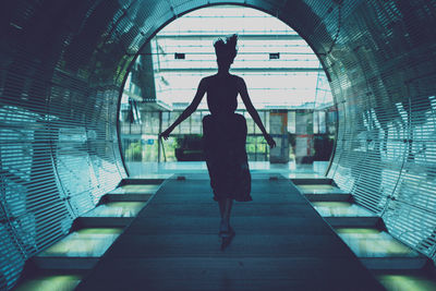 Rear view of silhouette woman walking in tunnel