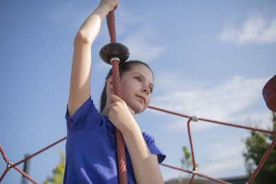 Low angle view of boy looking at camera against sky