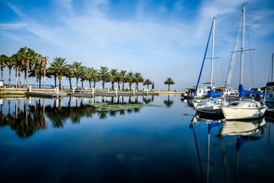 Sailboats moored on river against cloudy sky