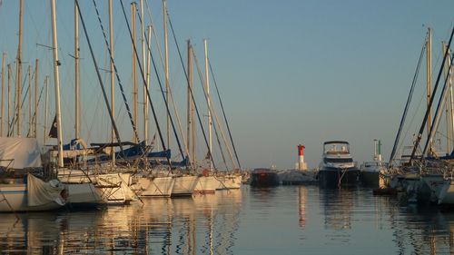 Sailboats moored in sea against clear sky