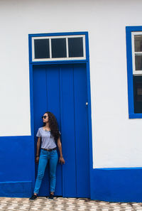 Full length of woman standing against blue building